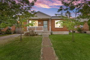View of front of home featuring a lawn, a porch, and brick siding
