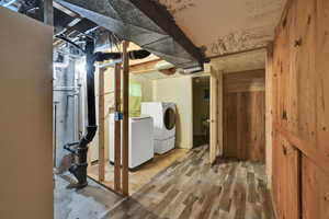 Unfinished below grade area featuring washing machine and dryer and wood finished floors