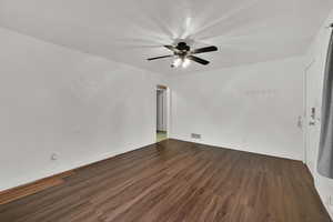 Empty room featuring dark wood-type flooring and a ceiling fan