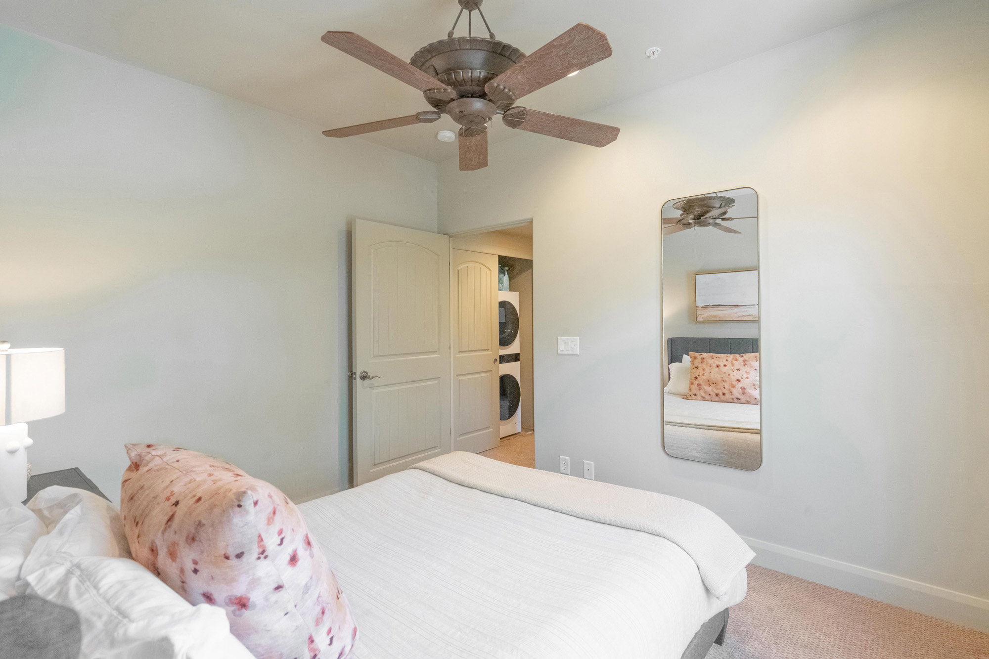 Carpeted bedroom featuring estacked washer and dryer and a ceiling fan