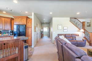 Living area with recessed lighting, light colored carpet, and stairs