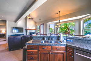 Kitchen featuring a tiled fireplace, stainless steel dishwasher, vaulted ceiling, dark colored carpet, and a chandelier