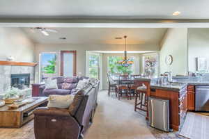 Living area featuring light carpet, a chandelier, a fireplace, and ceiling fan