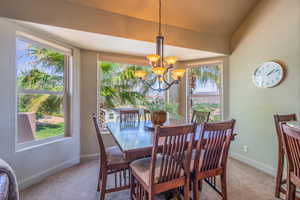 Dining room featuring light carpet, a chandelier, and vaulted ceiling