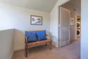 Living area with carpet flooring and stacked washer and clothes dryer
