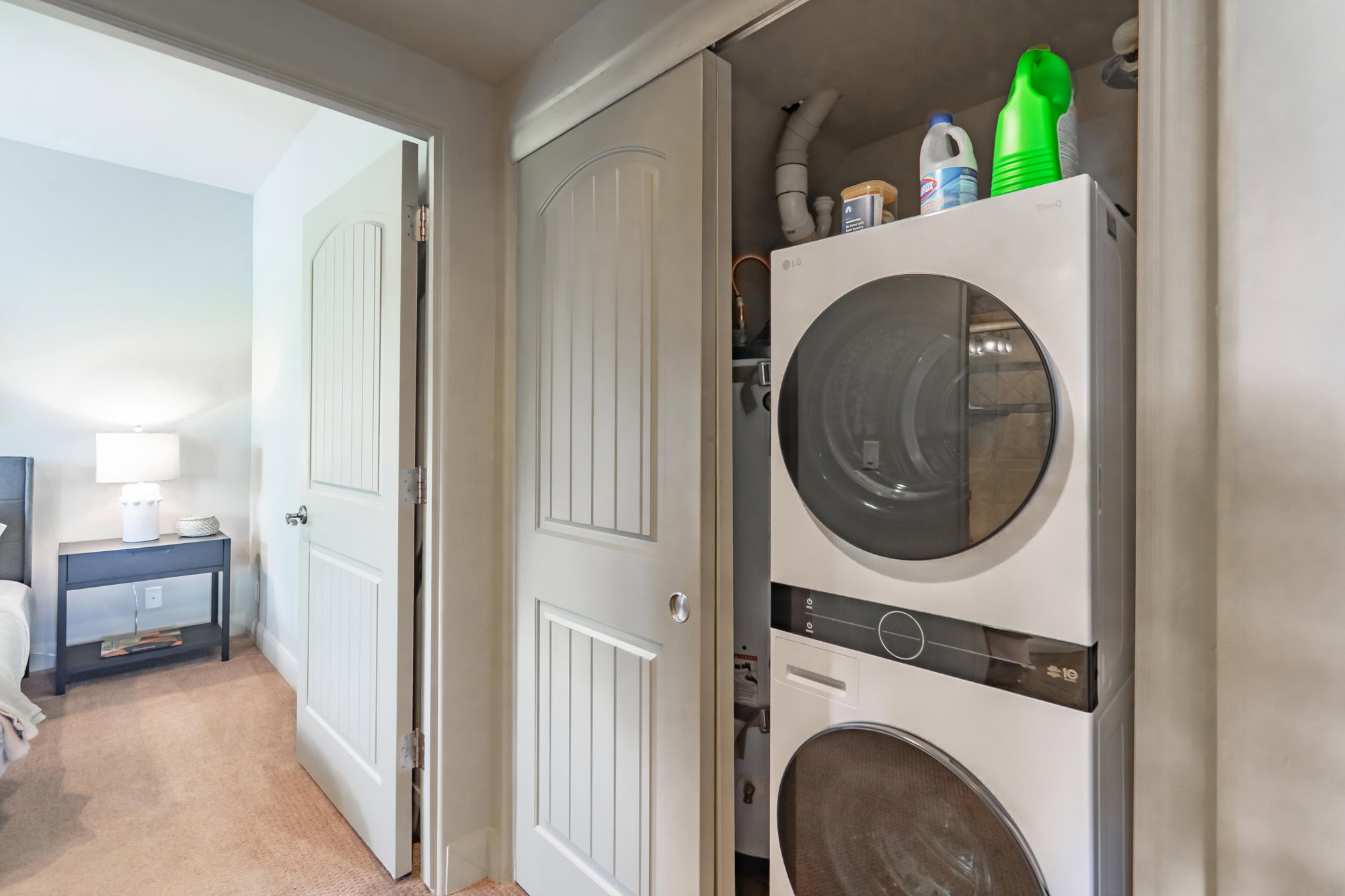 Laundry area featuring estacked washer and dryer and light colored carpet