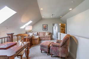 Carpeted living room with a skylight, vaulted ceiling, and recessed lighting