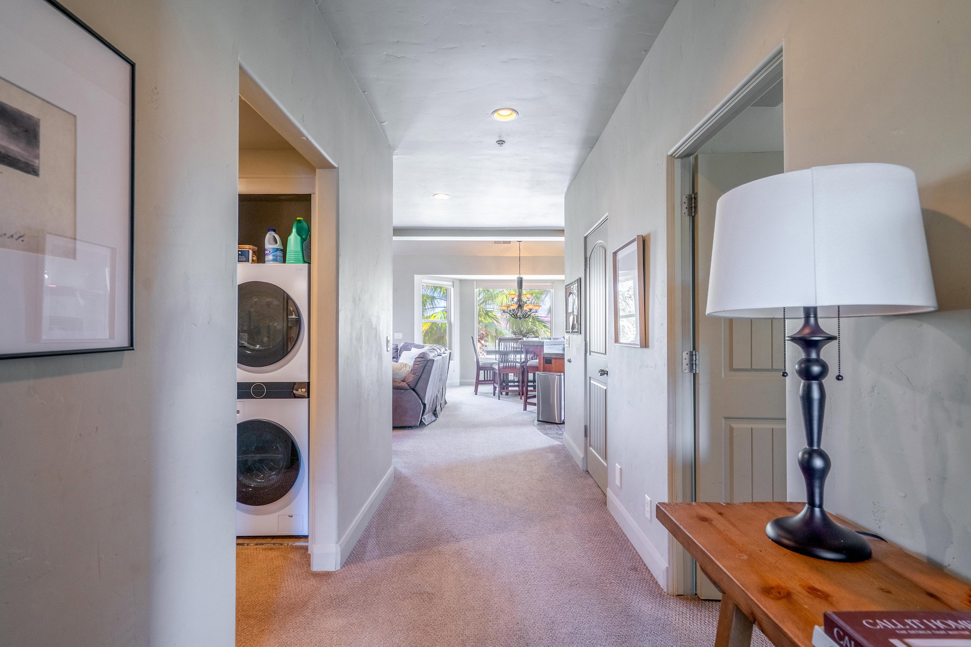Hall with light carpet and stacked washing machine and dryer