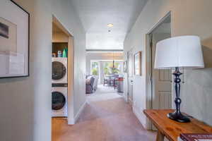 Hall with light carpet and stacked washing machine and dryer