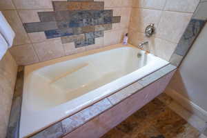 Full bath with a garden tub and tile patterned flooring