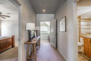 Hall with light colored carpet and baseboards