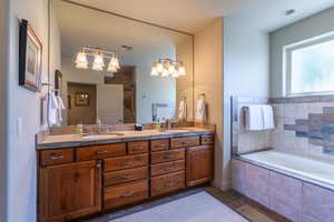 Bathroom featuring double vanity, a garden tub, and dark tile patterned floors
