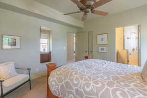 Bedroom with ensuite bath, light carpet, and a ceiling fan