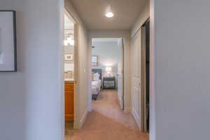 Hallway with light colored carpet and baseboards