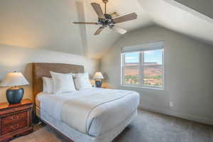 Carpeted bedroom featuring lofted ceiling and a ceiling fan
