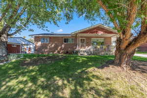 View of front of home featuring a front lawn, brick siding, and a porch