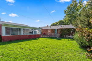 View of grassy yard featuring a sunroom