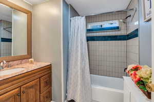 Bathroom featuring shower / bath combo, vanity, and a textured ceiling