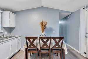 Dining room with light wood-type flooring and vaulted ceiling