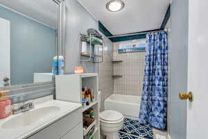 Full bathroom with vanity, shower / bathtub combination with curtain, and a textured ceiling