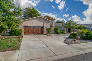 View of front of house with brick siding, driveway, a garage, and stucco siding