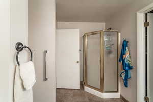 Bathroom with a stall shower, a textured ceiling, and tile patterned flooring