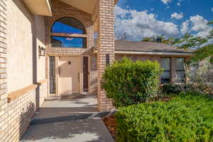 Entrance to property featuring brick siding and roof with shingles