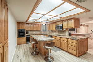 Kitchen with a breakfast bar, tasteful backsplash, oven, a peninsula, and brown cabinets