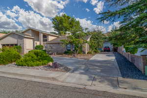 View of front facade with brick siding, concrete driveway, and stucco siding