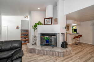 Living room featuring light wood-type flooring, a multi sided fireplace, and recessed lighting