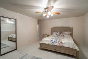 Carpeted bedroom with a ceiling fan, a textured ceiling, and a closet