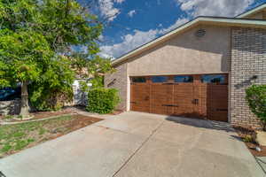 View of home's exterior with brick siding, concrete driveway, a garage, and stucco siding