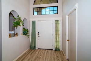 Entrance foyer with light wood finished floors and a towering ceiling