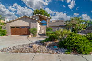 View of front of property featuring brick siding, concrete driveway, a garage, and a chimney