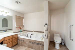 Full bathroom featuring a tub with jets, vanity, and light tile patterned floors