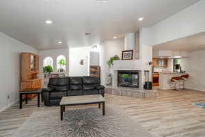 Living area with light wood finished floors, recessed lighting, and a glass covered fireplace