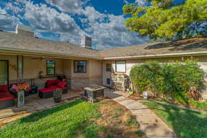 Back of property featuring stucco siding, an outdoor living space with a fire pit, brick siding, a chimney, and a ceiling fan