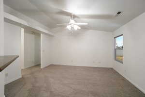 Spare room featuring vaulted ceiling, light carpet, and ceiling fan