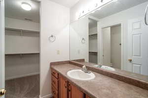 Full bath featuring vanity, dark carpet, and a walk in closet