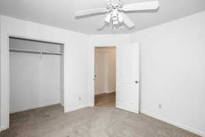 Unfurnished bedroom with light carpet, ceiling fan, and a closet