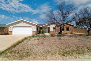 Single story home with driveway, a garage, and brick siding