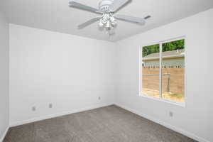 Empty room featuring carpet floors and a ceiling fan