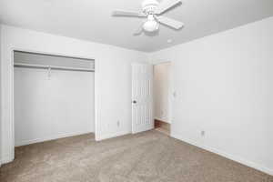 Unfurnished bedroom featuring carpet, ceiling fan, and a closet