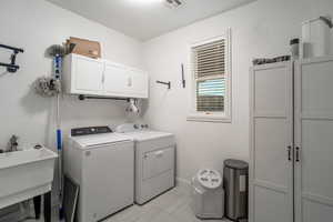 Laundry room featuring light tile patterned floors, cabinet space, and washer and clothes dryer
