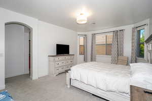 Bedroom featuring arched walkways and light colored carpet