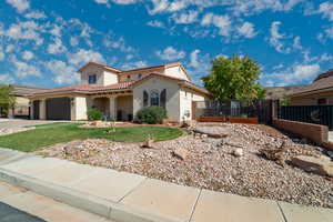 Mediterranean / spanish-style home with stucco siding, a gate, a tiled roof, an attached garage, and driveway