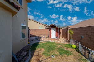 Fenced backyard featuring a storage shed and a patio area