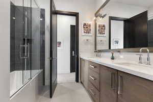 Bathroom featuring shower / bath combination with glass door, double vanity, and contemporary cabinets & fixtures