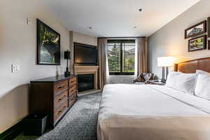 Bedroom featuring dark colored carpet and a glass covered fireplace