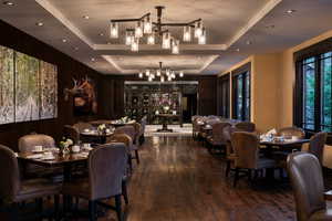 Dining room featuring a tray ceiling, dark wood-style floors, a chandelier, and recessed lighting